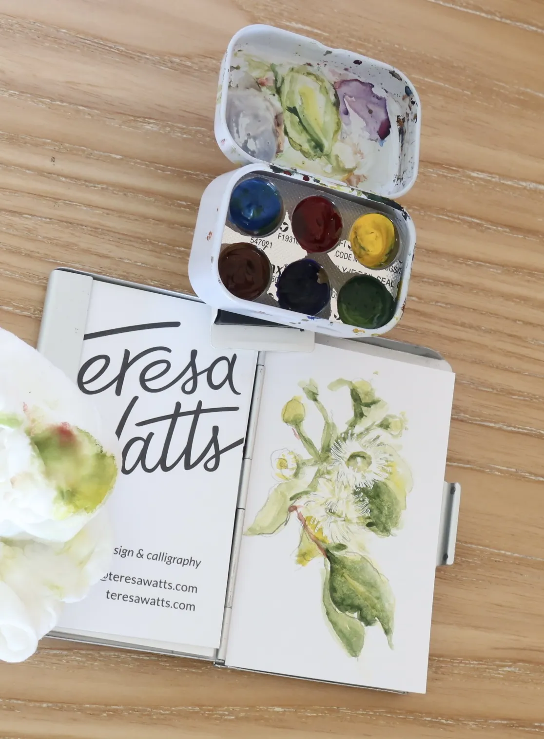 Photo of my tiny watercolour palette attached to business card holder, with a painting of gum tree flowers